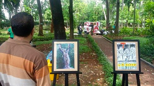 Pengunjung tengah menikmati dan mengamati karya lukis Andreas Iswinarto di ajang Climate Art Day. Foto: Indra Nugraha
