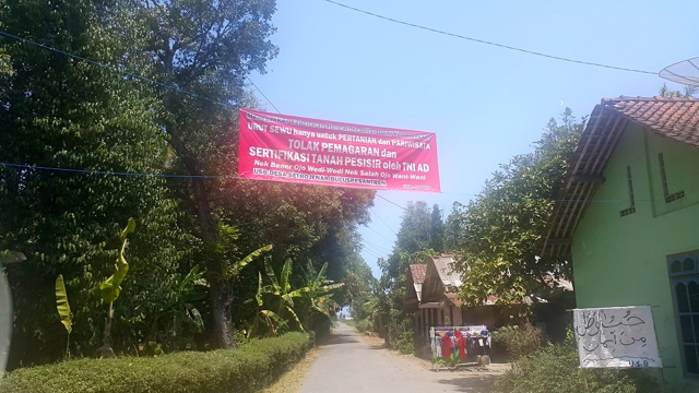 Spanduk penolakan pemagaran dan latihan militer di Desa Setrojenar, Kecamatan Buluspesanter terpasang di jalan desa menuju Dislitbang TNI. Foto: Tommy Apriando