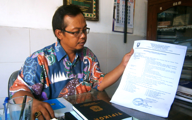 Kepala Desa Sikayu, Buayan, Kebumen, Teguh Prihatin memperlihatkan surat pengumuman permohonan izin lingkungan PT Semen Gombong. Foto: Nuswantoro