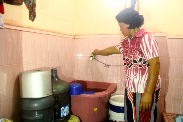 Junita, warga Gang Pelita cukup memutar keran untuk memperoleh air bersih. Foto: Tommy Apriando