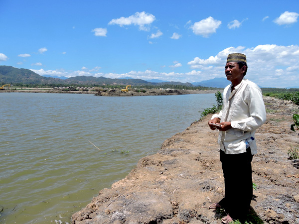 Sutarjo memperlihatkan tanah warga yang telah dikeruk dan berubah menjadi danau. Ia menagih pembayaran ganti rugi untuk tanah tersebut. Foto: Christopel Paino