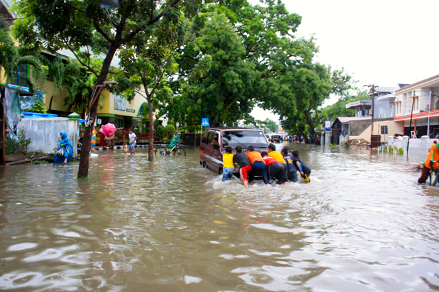  Anak-anak mndorong mobil mogok di tengah kepungan banjir. Foto: Vinolia