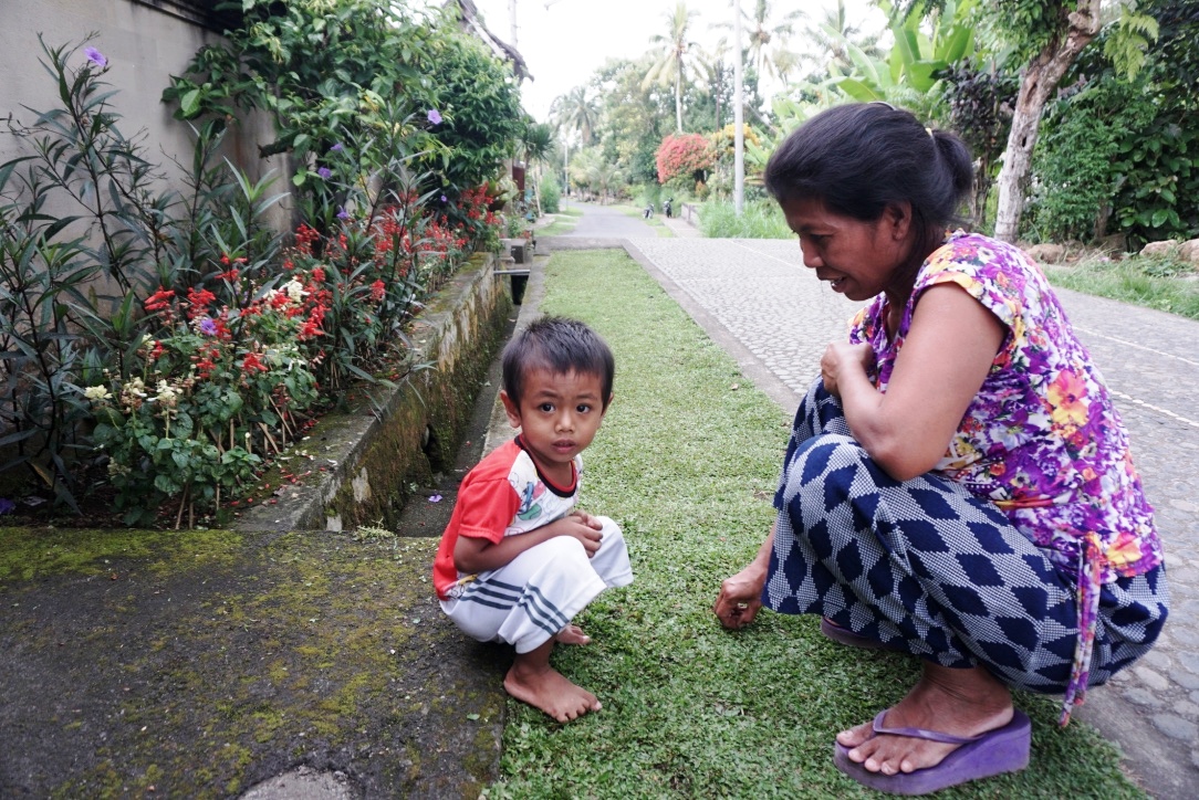 Seorang warga dan anaknya mencabut rumput di jalan utama di desa adat Penglipuran. Kecamatan Bangli, Kabupaten Bangli, Bali. Foto : Anton Muhajir