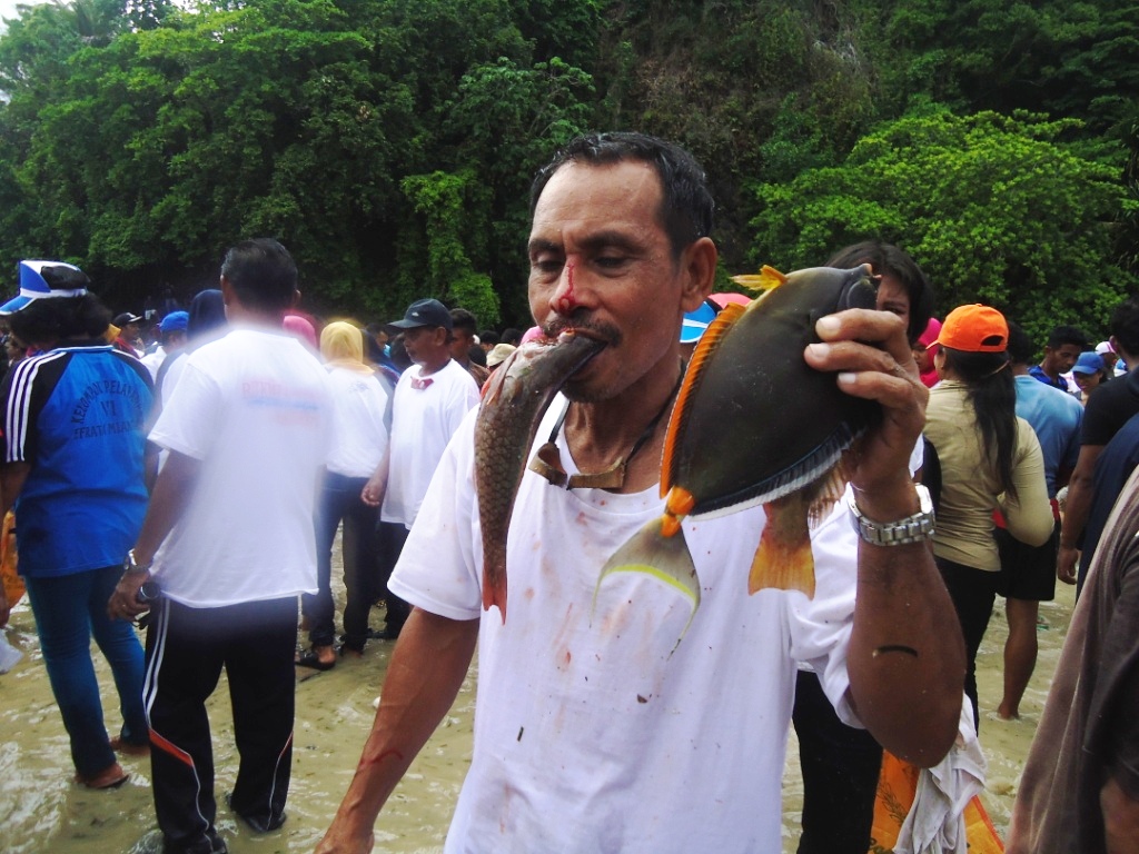 Seorang warga Pulau Miangas, Kabupaten Kepulauan Talaud, Sulut, menggigit ikan hasil tangkapannya dalam acara manam'mi pada Sabtu (21/5/2016). Manam'mi merupakan acara menangkap ikan secara tradisional. Foto : Themmy Doaly