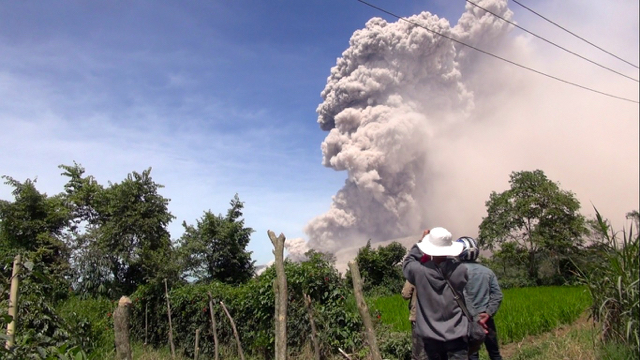 Warga menyaksikan Gunung Sinabung tengah erupsi mengeluarkan debu panas dan lahar dingin. Foto: Ayat S Karokaro
