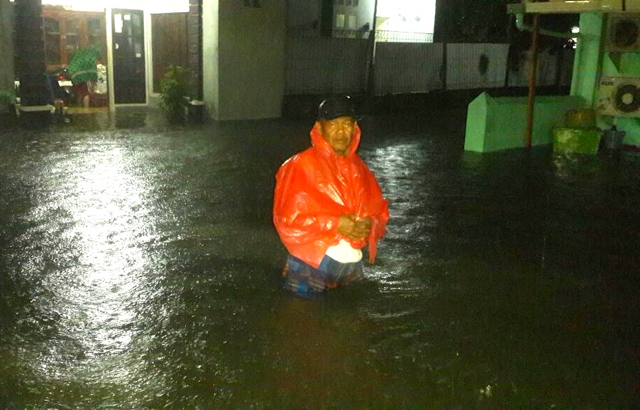 Seorang warga terjebak banjir di jalan Tarandam simpang empat kamis malam. Foto: Vinolia