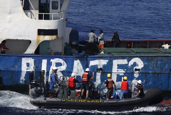 Aktivis Greenpeace menuliskan kata ‘pirate’ pada kapal illegal di perairan zona ekonomi eksklusif Indonesia pada November 2011. Kapal itu merupakan kapal pencuri ikan (IUU Fishing) dengan jaring purse seine yang tidak terdapat nama di lambung kapalnya. Foto : Greenpeace