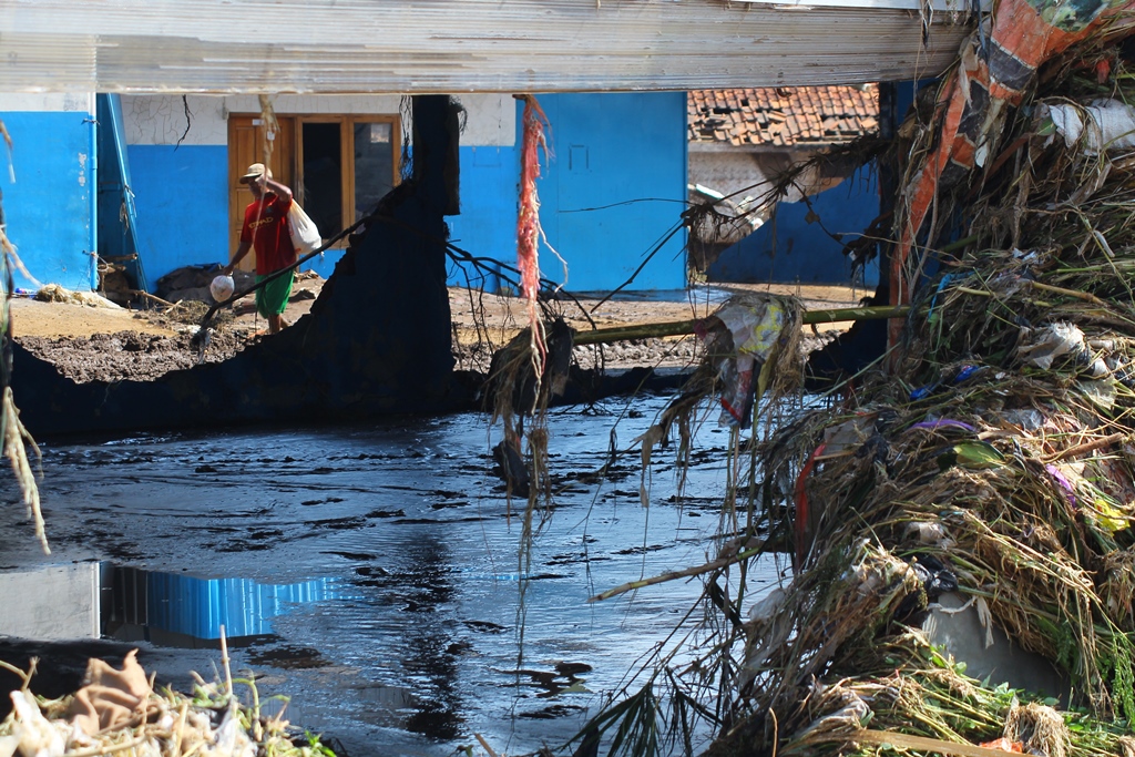 Warga melintas di bangunan yang hancur di Kampung Cimacan, Kecamatan Tarogongkidul, Kabupaten Garut, Jabar, Kamis,(22/09/2016). Banjir Bandang juga menghancurkan instalasi PDAM sehingga warga banyak yang kesulitan mendapat air bersih. Foto : Donny Iqbal