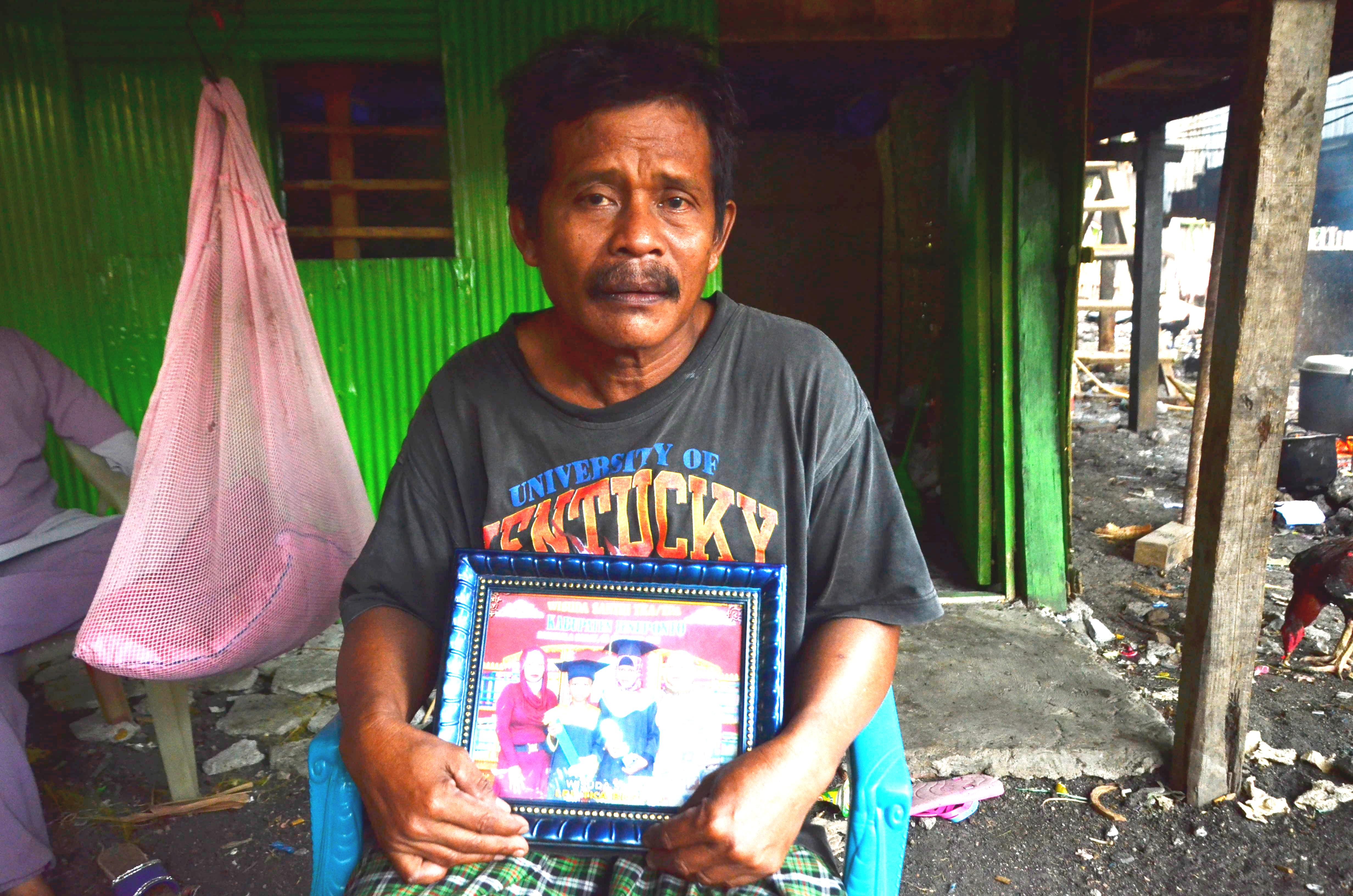 Daeng Amin yang berprofesi sebagai buruh bangunan ini memperlihatkan foto istrinya, Daeng Bombong, yang meninggal akibat keracunan kerang yang mengadung arsenik dan sianida. Sesaat setelah menyantap kerang Daeng Bombong langsung kejang-kejang dan tak sadarkan diri. Foto: Wahyu Chandra