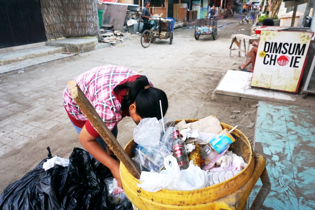 Seorang warga mengambil sampah sampah botol plastik dari tempat sampah di Gili Trawangan, NTB. Foto : Anton Muhajir