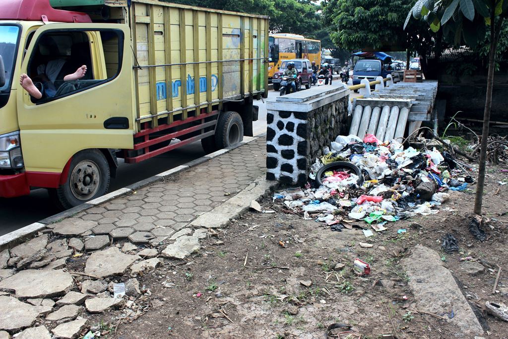 Seorang pengemudi beristirahat di mobilnya yang berdekatan dengan tumpukan sampah di Jalan Soekarno - Hatta, Kota Bandung. Tumpukan sampah sering dijumpai di pinggiran kota yang kadang terlambat untuk diangkut ke TPA. Foto : Donny Iqbal