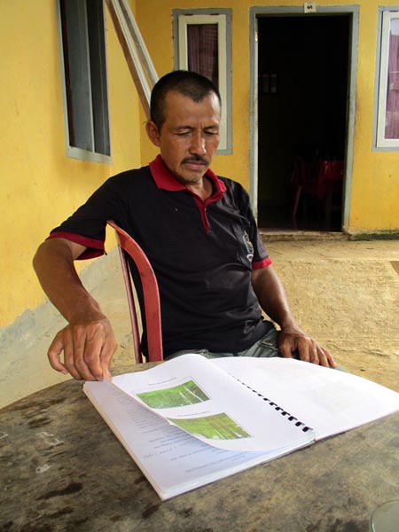Saryono memperlihatkan dokumen kesepakatan dan peraturan desa yang bertujuan melindungi hutan sekaligus habitat harimau sumatera. Foto: Dedek Hendry