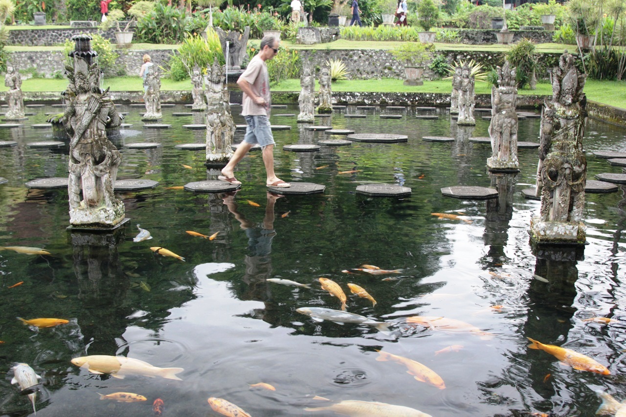 Pengunjung berjalan seperti di atas permukaan kolam dengan banyak patung epos Mahabrata penuh ikan mas di Taman Tirtagangga, Karangasem, Bali | Foto: Anton Muhajir