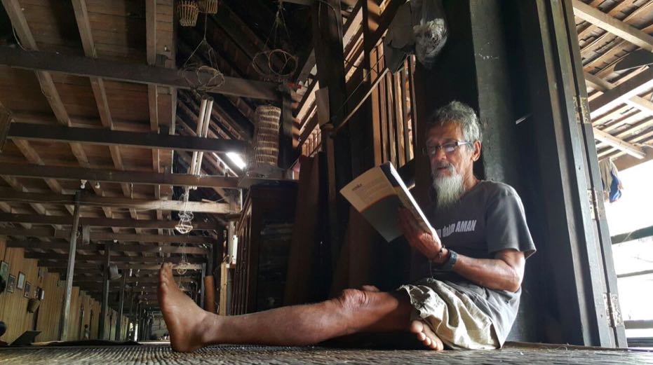 Apai Janggut sedang membaca. Apai adalah pimpinan di rumah betang Sungai Utik, tokoh penyelamat hutan adat Sungai Utik | Foto: Yani Saloh/Mongabay Indonesia