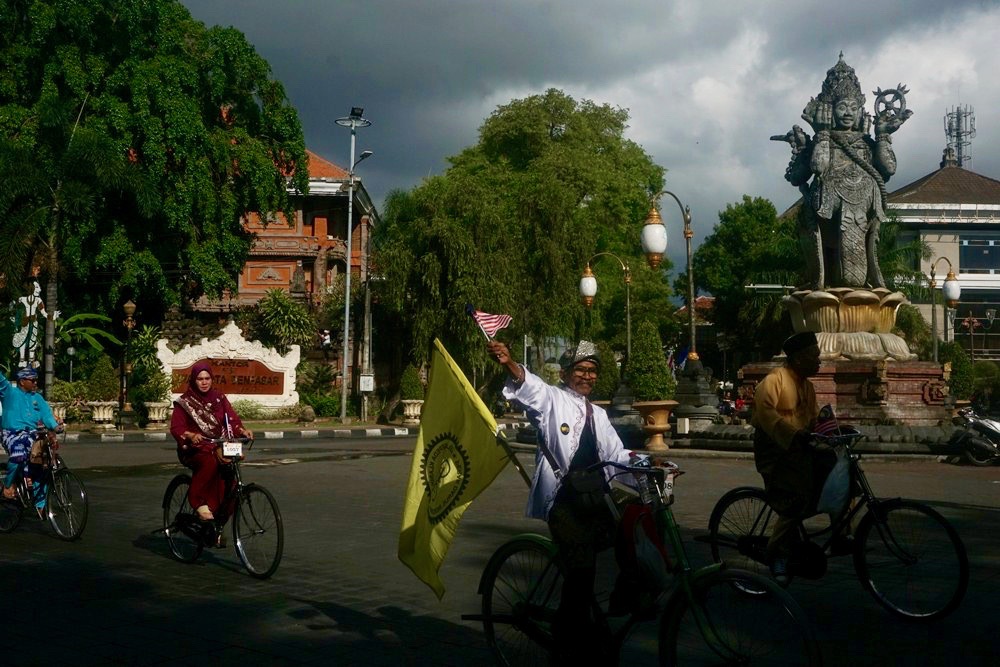 Peserta dari Malaysia menunjukkan ngonthel dengan pakaian melayu saat melewati landmark kota Denpasar, Patung Catur Muka. Foto: Luh De Suriyani/Mongabay Indonesia
