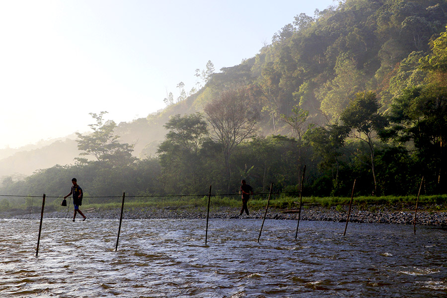 Warga Agusen menyeberang sungai di pagi hari menggunakan jembatan dari kawat | Foto: Junaidi Hanafiah/Mongabay Indonesia