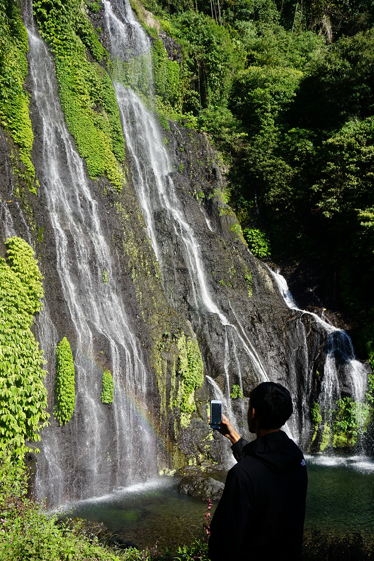 Seorang pengunjung mengabadikan keindahan air terjun Banyumala. Air terjun setinggi sekitar 20 meter ini terletak di lembah Desa Wanagiri. Foto : Ahmad Muzakky/Mongabay Indonesia