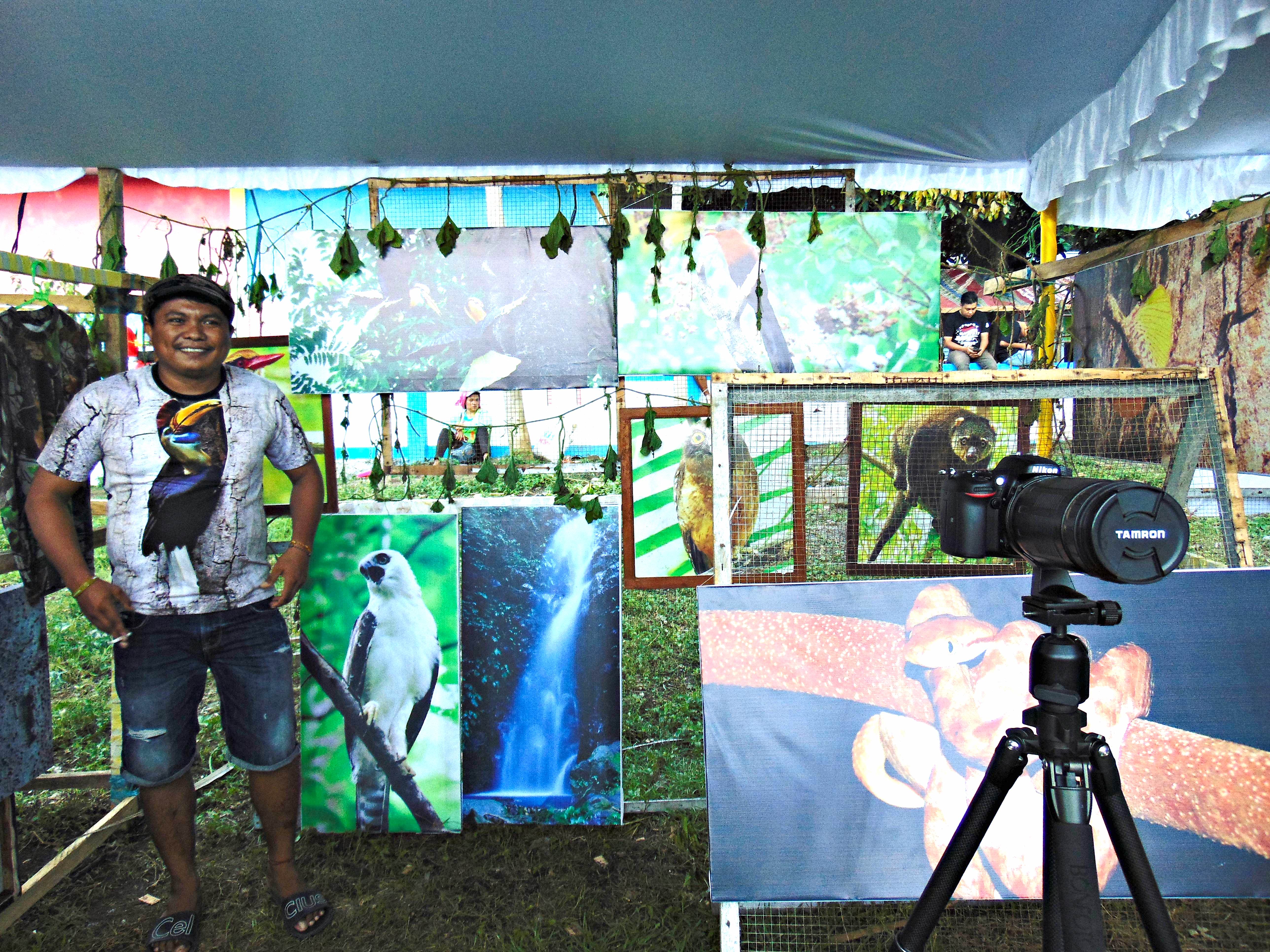  Alfred Masala, anggota Tukang Foto Orang Batuputih (T-FOB) di standnya yang memajang berbagai karya foto dari Cagar Alam Tangkoko dalam rangkaian acara perayaan 100 tahun Tangkoko | Foto: Themmy Doaly/Mongabay Indonesia 