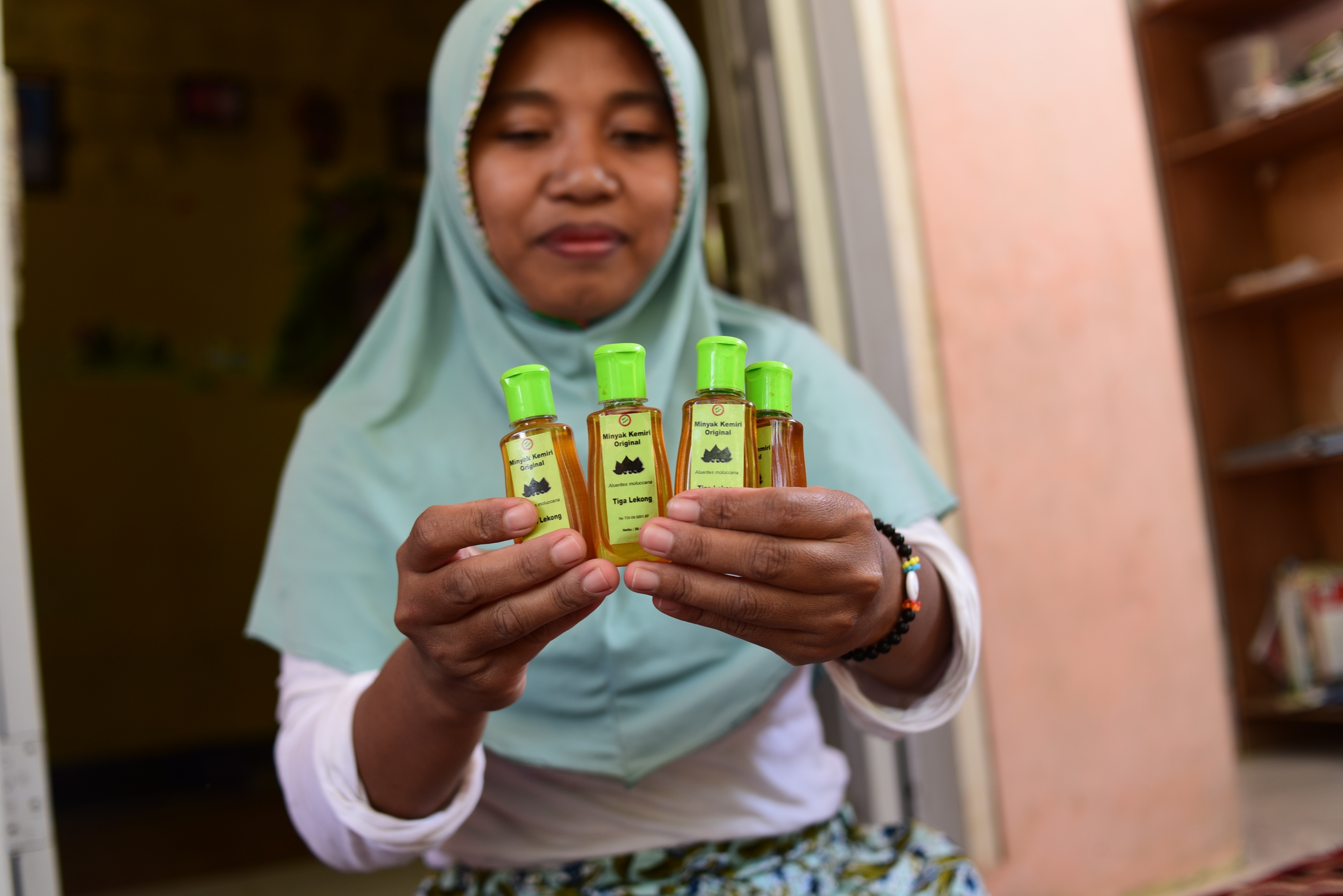 Eti Kamariani, menunjukkan minyak kemiri produksi kelompoknya. Perempuan petani HKm Tangga Desa Selengen, Lombok Utara kini membuat minyak kemiri untuk meningkatkan pendapatan mereka | Foto: Fathul Rakman/Mongabay Indonesia