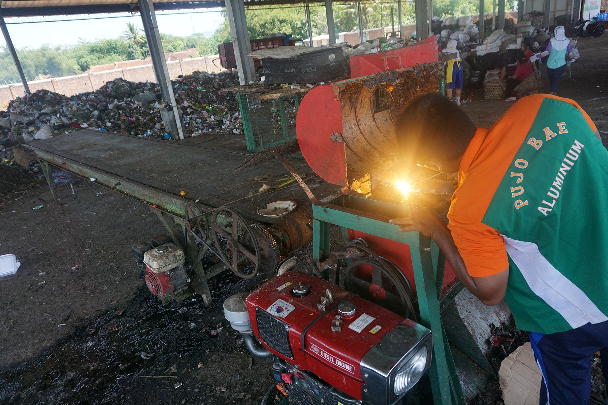  Pekerja tengah memperbaiki mesin pemilah sampah Pujo Bae | Foto: L Darmawan/Mongabay Indonesia 