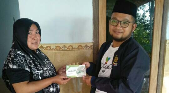 Ihsan menyerahkan buku tambungan bank sampah kepada salah satu nasabah. Foto: Gafur Abdullah/ Mongabay Indonesia
