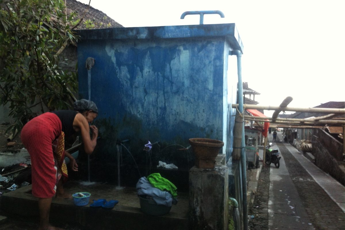 Seorang warga memanfaatkan air bersih di bak penampungan depan rumahnya. Foto: Nuswantoro/ Mongabay Indonesia