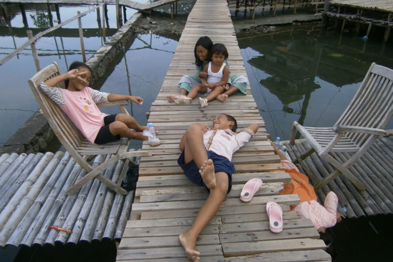 Anak-anak menikmati jembatan sepanjang 1,5 di Dukuh Timbulsloko. Setelah ada jembatan, warga tak lagi harus berjalan mengarunggi 'laut baru' atau bersampan untuk sampai ke dataran kering. Foto: Nuswantoro/ Mongabay Indonesia