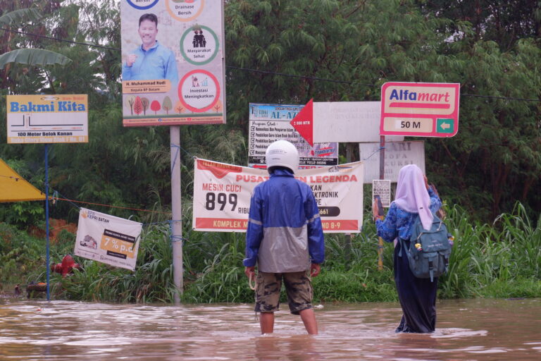 Dua-orang-warga-Batam-melintas-digenangan-banjir-yang-terjadi-di-ruas-jalan-di-Batam.-Foto-Yogi-Eka-Sahputra-scaled.jpg