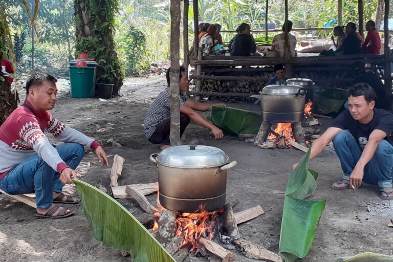  Menjaga api dengan daun pisang saat menanak pulut. Foto Suryadi/ Mongabay Indonesia